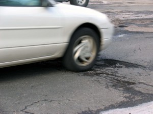 Car driving over pothole